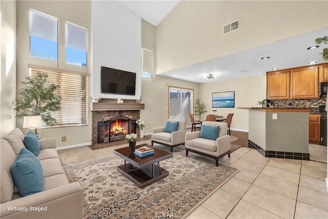 living room with a towering ceiling, a premium fireplace, and light tile patterned flooring