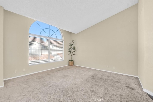 carpeted empty room with lofted ceiling