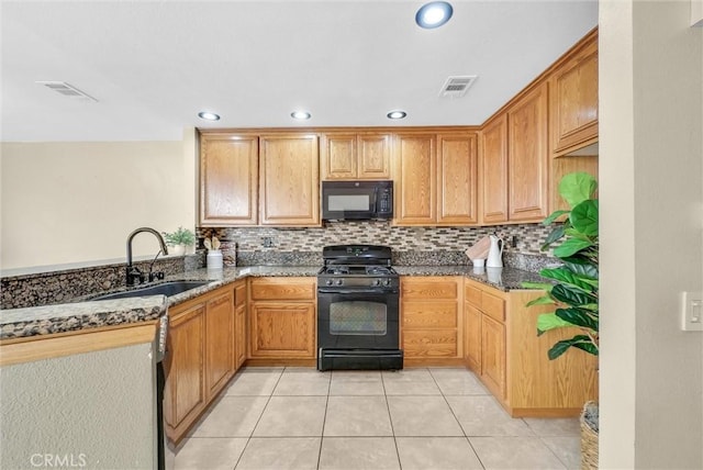 kitchen with decorative backsplash, light tile patterned flooring, dark stone countertops, black appliances, and sink