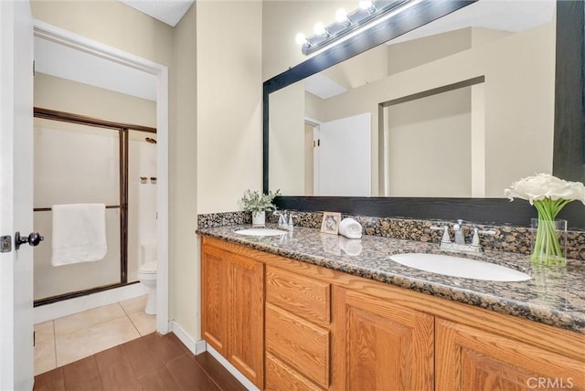 bathroom featuring toilet, vanity, tile patterned floors, and walk in shower