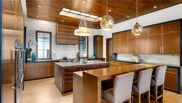 kitchen with wood ceiling, built in refrigerator, a center island, and hanging light fixtures