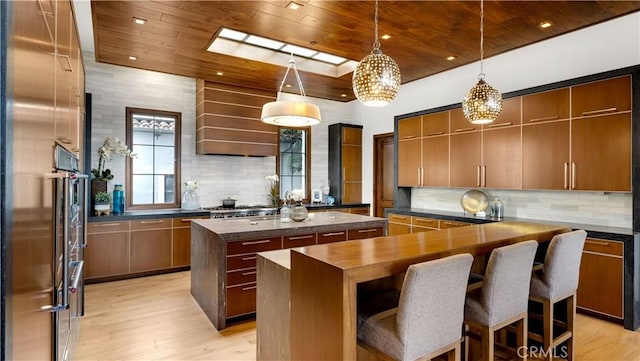 kitchen featuring backsplash, light wood-style flooring, a center island, and wood ceiling