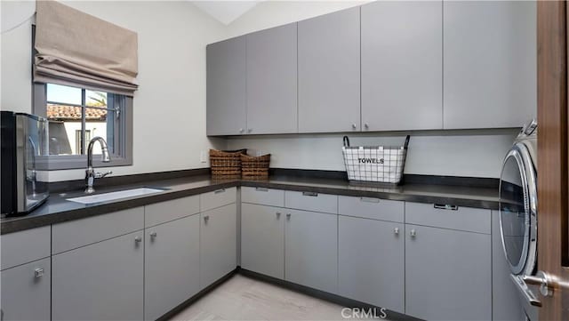 kitchen with gray cabinets, vaulted ceiling, and sink