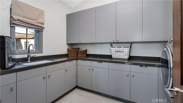 kitchen featuring washer / dryer, dark countertops, and a sink