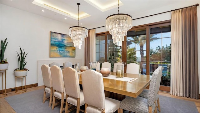 dining room featuring recessed lighting, an inviting chandelier, a raised ceiling, wood finished floors, and baseboards