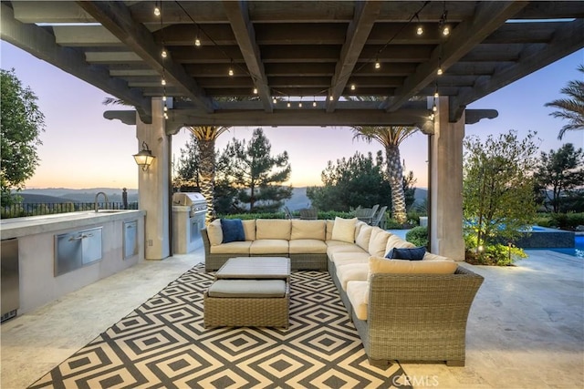 patio terrace at dusk with a grill, an outdoor hangout area, sink, and exterior kitchen