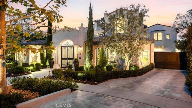 mediterranean / spanish house featuring french doors, driveway, an attached garage, and stucco siding