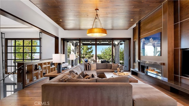 living room with hardwood / wood-style flooring, plenty of natural light, a premium fireplace, and wooden ceiling