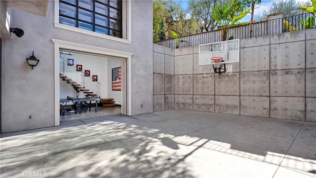 view of basketball court with fence and stairs