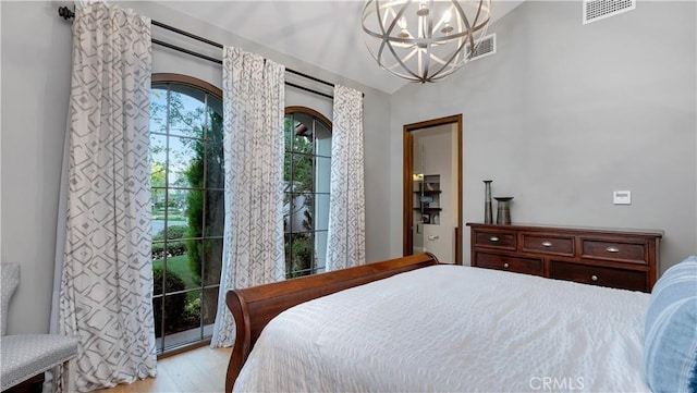 bedroom with a notable chandelier, access to exterior, and light wood-type flooring