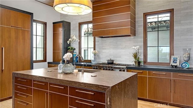2 Thomas Rd, Ladera Ranch, CA 92694 - kitchen with wall chimney range hood, plenty of natural light, a center island with sink, and tasteful backsplash
