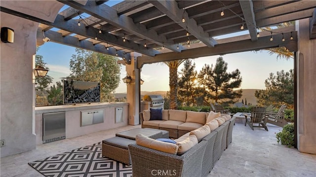 patio terrace at dusk with an outdoor living space, a pergola, an outdoor kitchen, and a grill