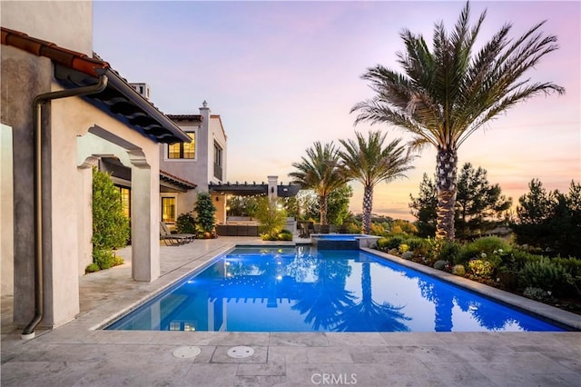 pool at dusk with a patio area and a pergola