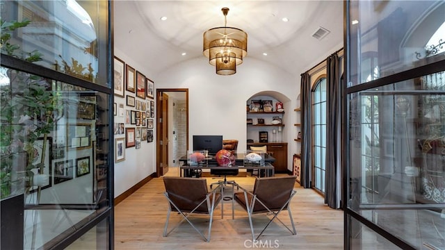 home office featuring a chandelier, light hardwood / wood-style floors, vaulted ceiling, and built in features