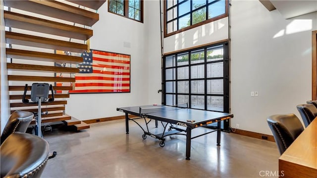 rec room featuring concrete flooring and a high ceiling