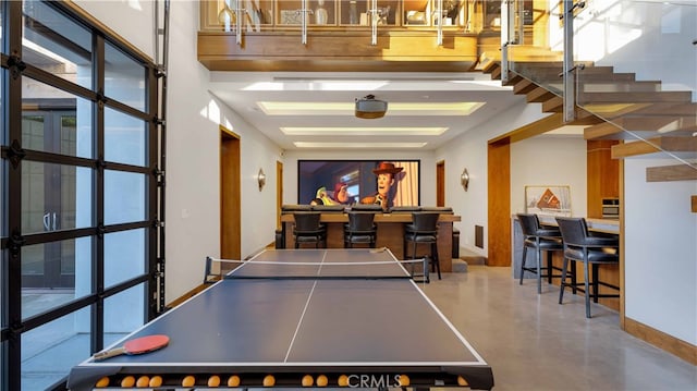 playroom featuring concrete flooring, a high ceiling, and bar area