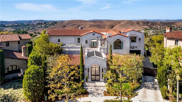 mediterranean / spanish-style house featuring a balcony, a mountain view, and stucco siding