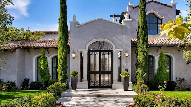 view of exterior entry with a tiled roof and stucco siding