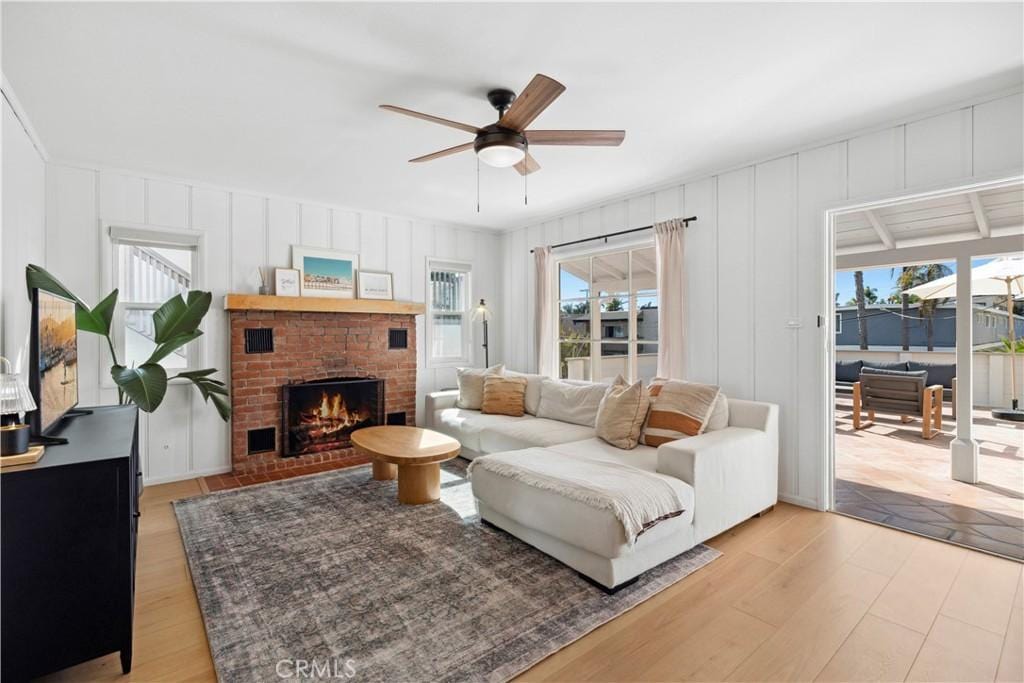 living room featuring ceiling fan, light hardwood / wood-style floors, a fireplace, and a healthy amount of sunlight