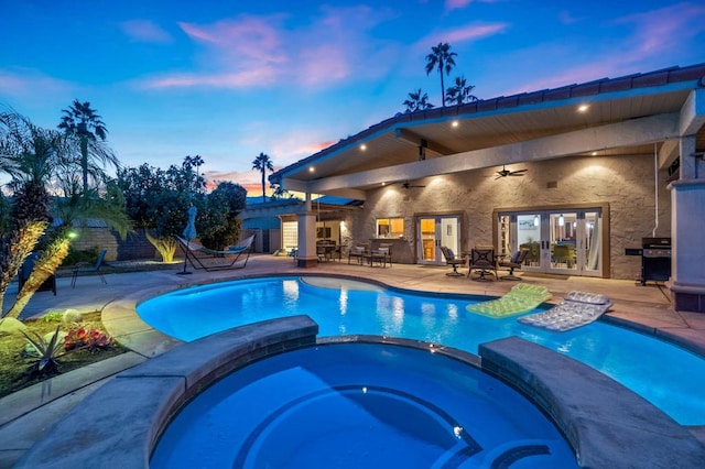 pool at dusk featuring ceiling fan, french doors, a patio, and an in ground hot tub