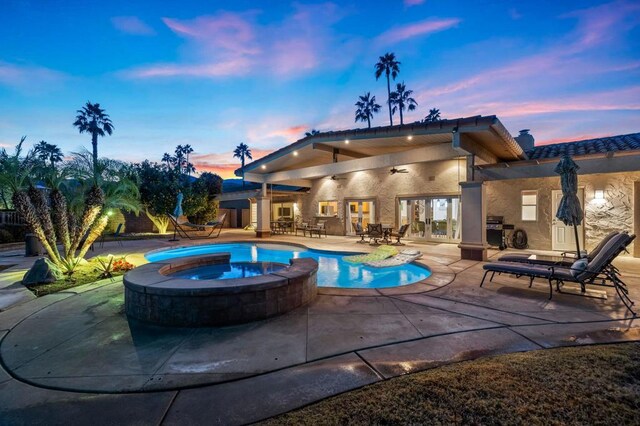 pool at dusk with an in ground hot tub, a grill, ceiling fan, and a patio