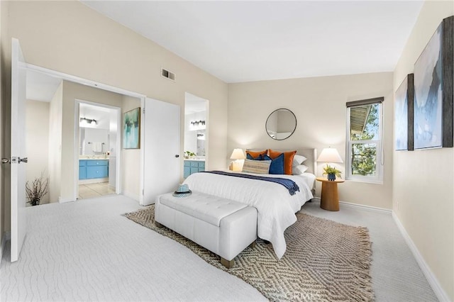 bedroom with ensuite bath and light carpet