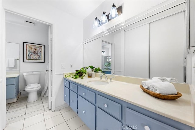 bathroom with toilet, tile patterned floors, and vanity