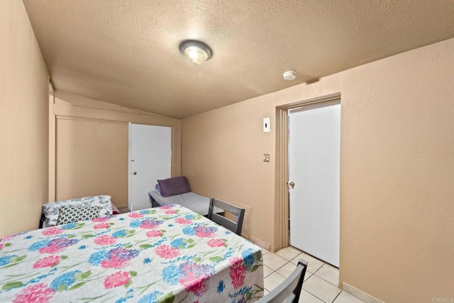 tiled bedroom featuring a closet, vaulted ceiling, and a textured ceiling