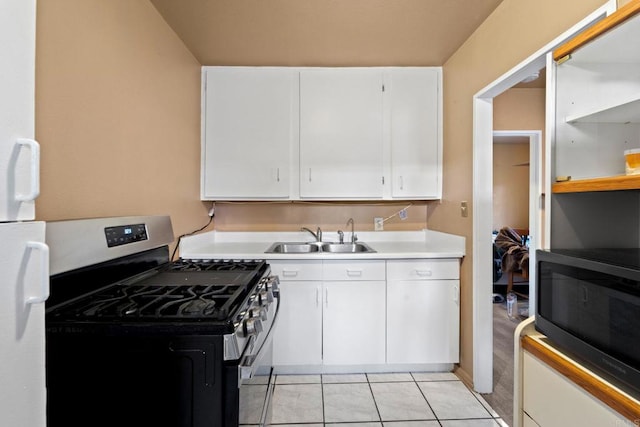 kitchen featuring white cabinetry, stainless steel gas range oven, sink, and light tile patterned floors