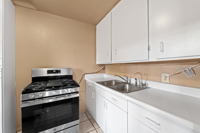 kitchen with white cabinetry, light tile patterned floors, sink, and stainless steel gas range oven