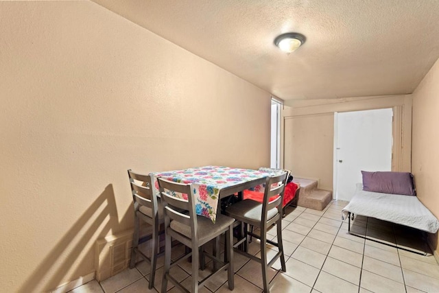 dining space with a textured ceiling and light tile patterned flooring