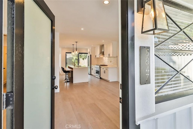 hall featuring an inviting chandelier, light hardwood / wood-style floors, and sink