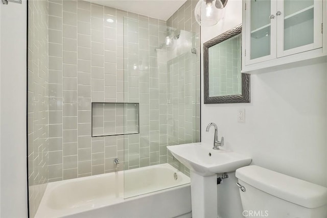 bathroom featuring toilet and tiled shower / bath