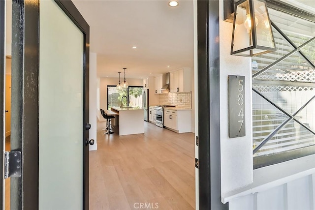 hall featuring sink, light wood-type flooring, and a notable chandelier