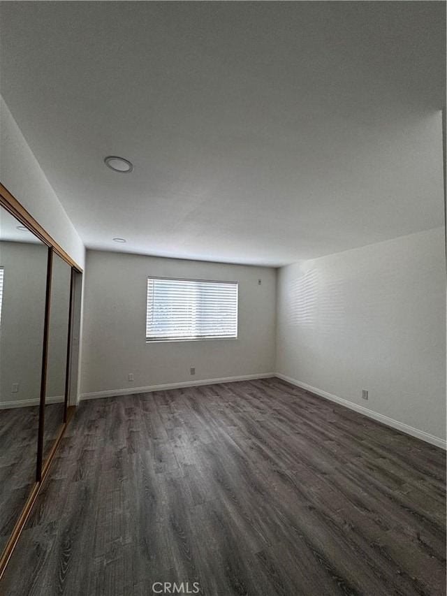 unfurnished bedroom featuring dark wood-type flooring and a closet