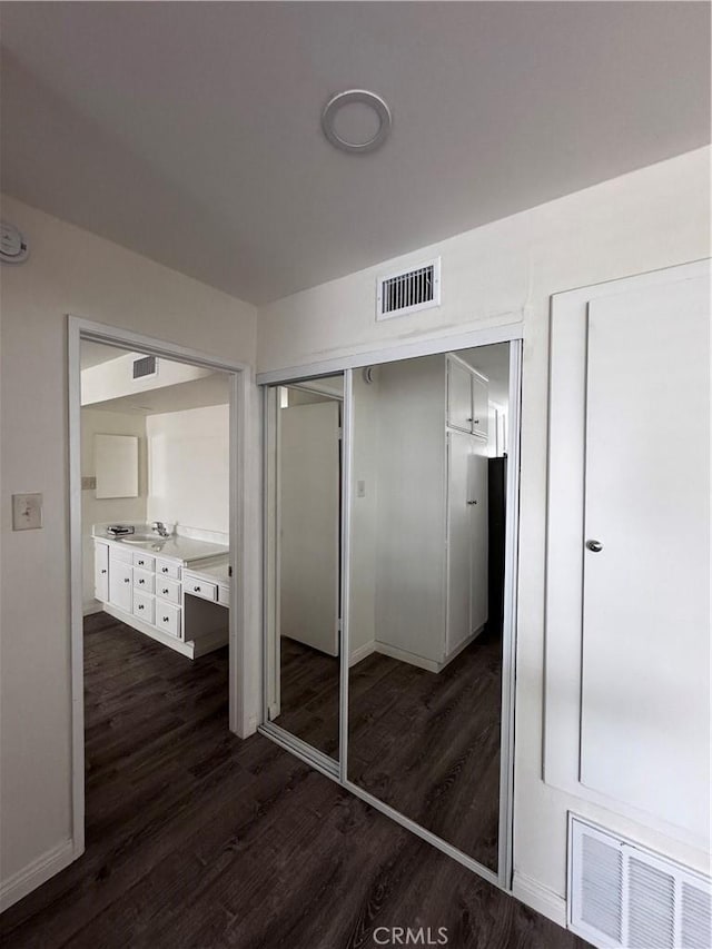 unfurnished bedroom featuring a closet, dark hardwood / wood-style floors, and sink