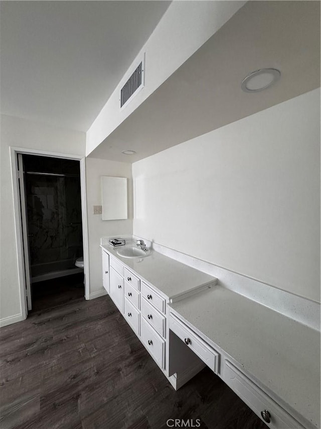 kitchen with dark wood-type flooring, white cabinetry, and sink