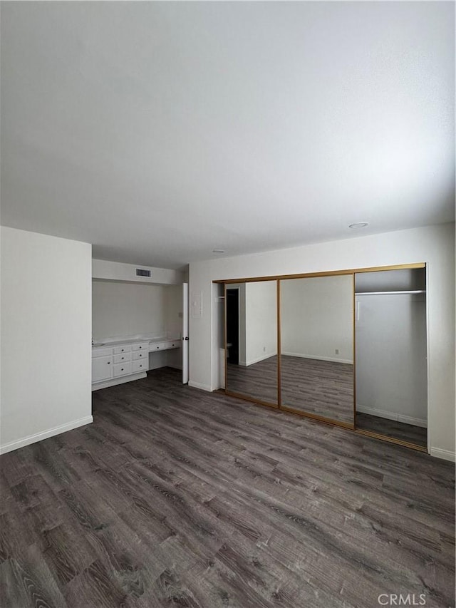 unfurnished bedroom featuring a closet and dark hardwood / wood-style floors