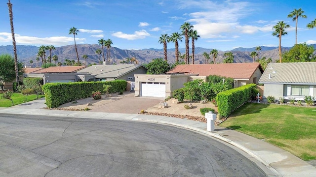 ranch-style home featuring a mountain view, a front yard, and a garage