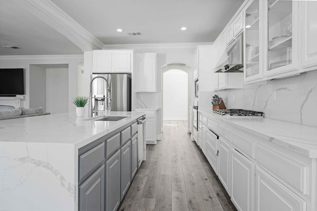 kitchen with appliances with stainless steel finishes, white cabinetry, ornamental molding, light stone counters, and gray cabinetry