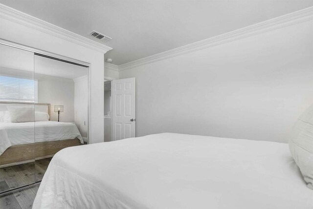 bedroom with hardwood / wood-style floors, a closet, and crown molding