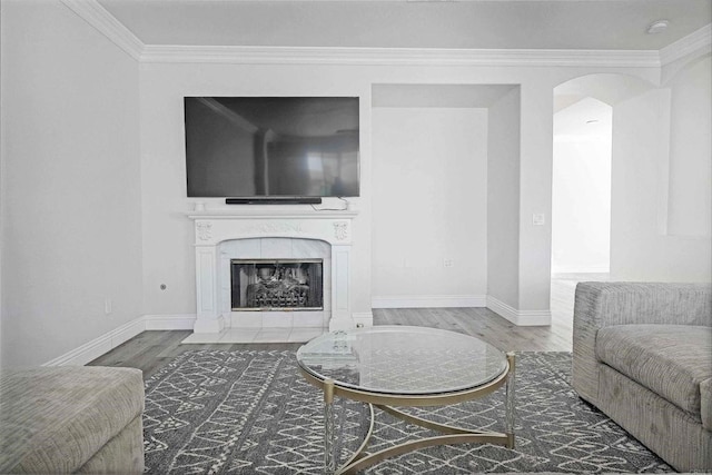 living room with wood-type flooring, ornamental molding, and a tiled fireplace