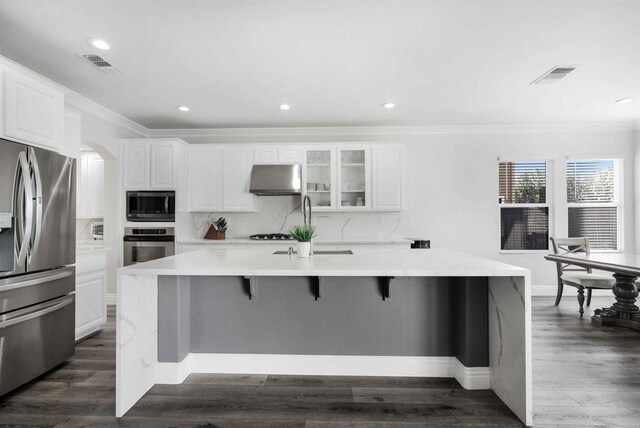 kitchen with a spacious island, appliances with stainless steel finishes, extractor fan, and white cabinetry