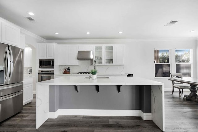 kitchen with a spacious island, white cabinets, stainless steel appliances, and range hood