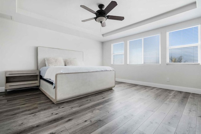 bedroom featuring a raised ceiling, ceiling fan, and wood-type flooring