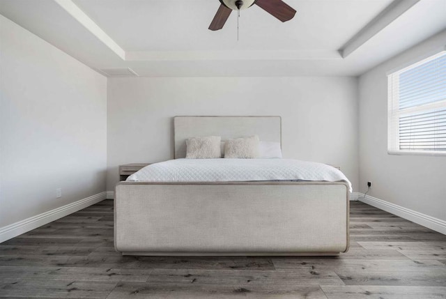 bedroom featuring ceiling fan, hardwood / wood-style floors, and a tray ceiling