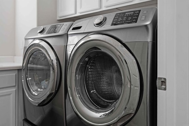 clothes washing area featuring washer and dryer and cabinets