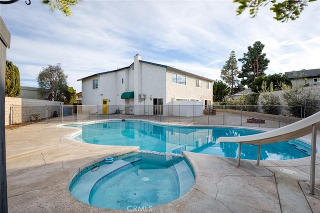 view of swimming pool featuring a patio area, an in ground hot tub, and a water slide