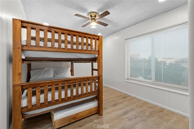 bedroom with a textured ceiling, ceiling fan, and light hardwood / wood-style floors