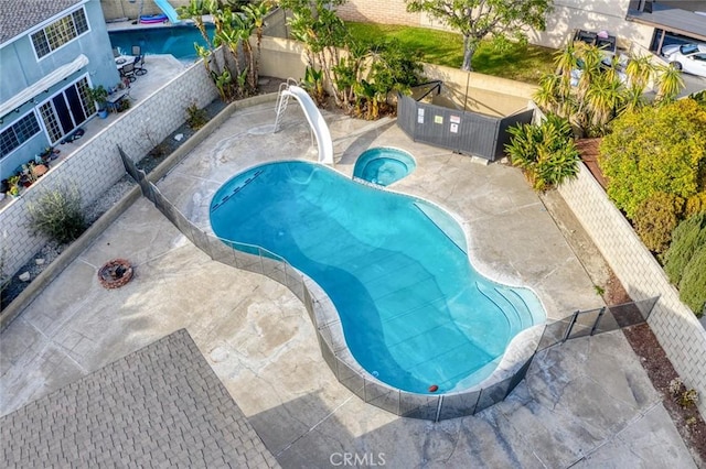 view of swimming pool with a water slide, a patio, and an in ground hot tub